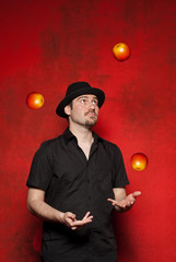 Young man juggling on a red background