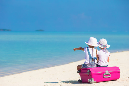 Little girls with big suitcase and map at tropical beach