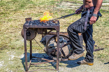 Metal being worked by craftsman at a blacksmith forge .