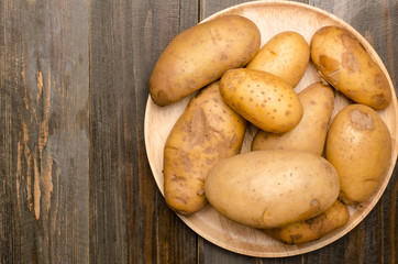 Raw potatoes on wooden plate