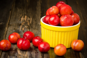 Fresh plum (Julee) in the bowl on wooden background