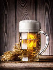 Faceted mug of light beer with foam and ears