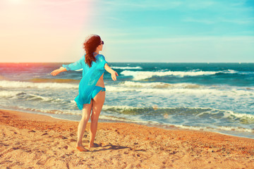 Happy young woman walking on the beach