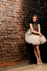 ballerina in tutu near brick wall