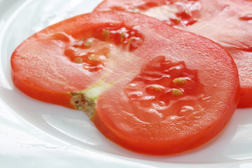 sliced tomato on white plate.
