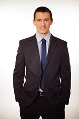 Young businessman in suit standing with hands in pockets