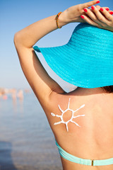 Woman With Suntan Lotion At The Beach In Form Of The Sun
