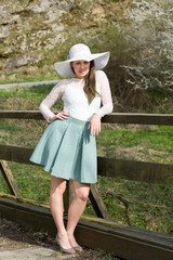 Obraz premium Cheerful fashionable woman in stylish hat and frock posing