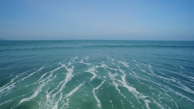 Idyllic aerial drone footage of tidal sea waves against clear sky. Tracking shot of seascape with crashing waves. As the waves splash they create a texture from sea foam. HD 1080 video.