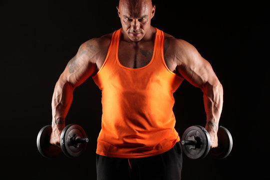 muscular bald man posing with weights on a black background