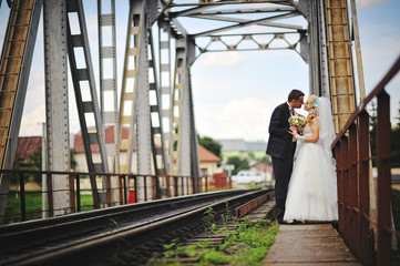 Young beautiful wedding couple at the train bridge