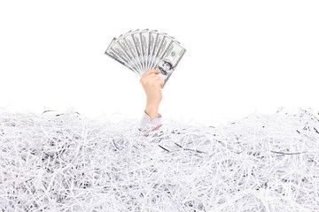 Hand holding money in a pile of shredded paper