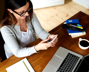 Woman sat at desk looking at mobile phone