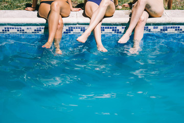 Women in swimsuit sitting on the edge of a pool