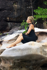 Young woman relaxing on big picturesque rock