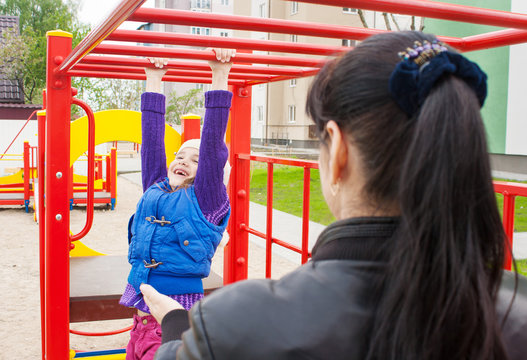 Mother Watching Play On The Playground Daughter