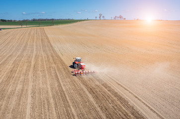Aerial view of the sunset above the tractor harrowing the field
