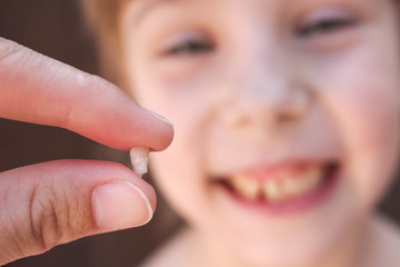  The girl is holding the tooth in his hand. 