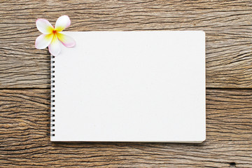 
Notebook and plumeria on wooden table
