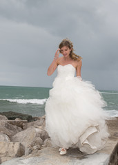 Fototapeta na wymiar Bride standing close to the ocean waiting for her lover