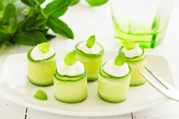 Rolls of cucumber with curd cheese and yogurt with mint.