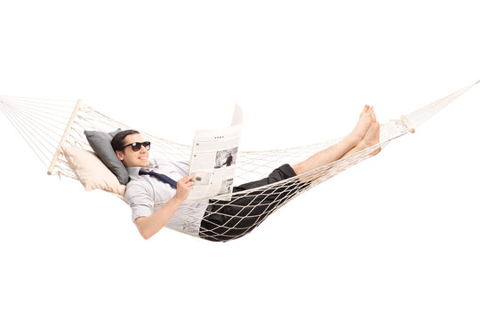 Relaxed man reading newspaper in a hammock