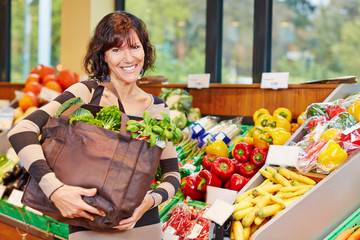 Smiling woman with bag full of vegetables