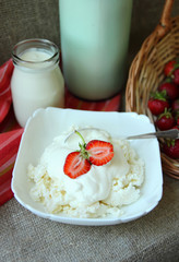 Dish of cottage cheese with sour cream and strawberries.