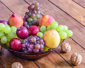Bowl with fresh,healthy and delicious fruits, on wooden table.