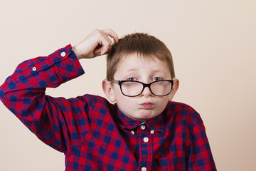 Confused little boy nerd ,holding a puzzle cube