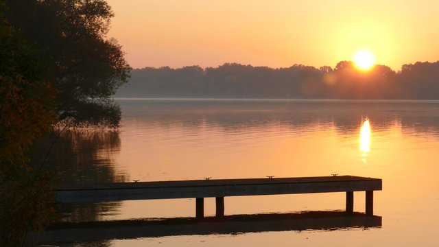 Sunrise over River With Jumping Fish
