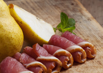 Pear and Italian ham on a board, selective focus