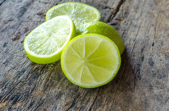 Slices limes on rustic wood background.