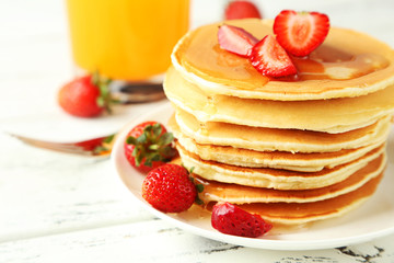 Delicious pancakes with strawberry on white wooden background