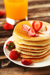 Delicious pancakes with strawberry on brown wooden background