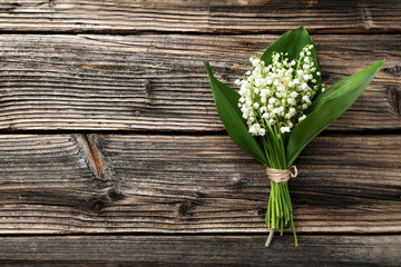 Lily of the Valley with leaves on brown wooden background