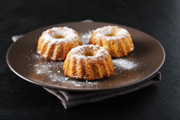 Bundt cakes on plate on black background