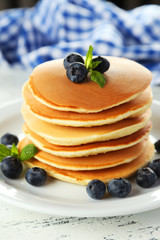 Delicious pancakes with blueberries on white wooden background