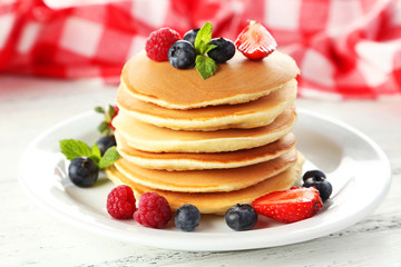 Delicious pancakes with berries on white wooden background