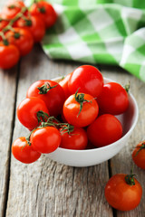 Fresh cherry tomatoes in bowl on grey wooden background