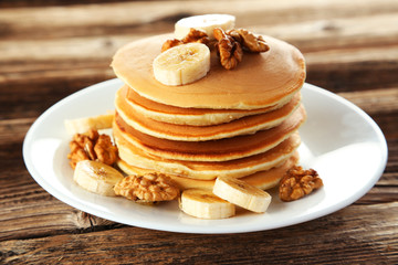 Delicious pancakes with banana on brown wooden background