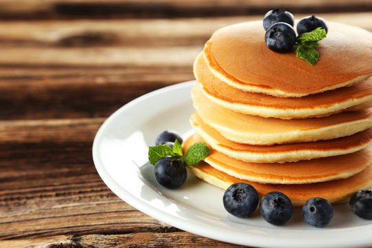 Delicious pancakes with blueberries on brown wooden background