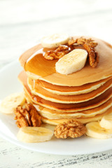 Delicious pancakes with banana on white wooden background
