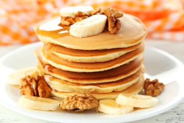 Delicious pancakes with banana on white wooden background