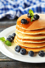 Delicious pancakes with blueberries on blue wooden background