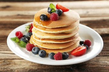 Delicious pancakes with berries on brown wooden background