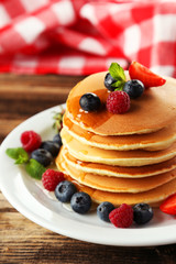 Delicious pancakes with berries on brown wooden background
