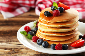 Delicious pancakes with berries on brown wooden background