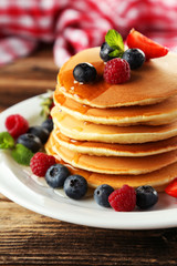 Delicious pancakes with berries on brown wooden background