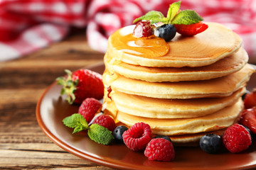 Delicious pancakes with berries on brown wooden background